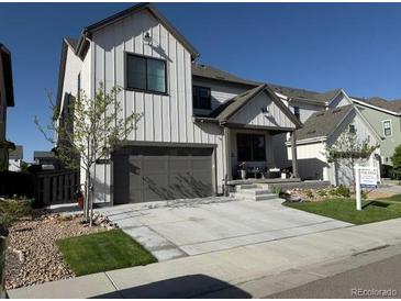 Charming two-story home with modern farmhouse design, featuring a gray garage door and a well-manicured lawn at 9140 Moondance Sw Dr, Littleton, CO 80125