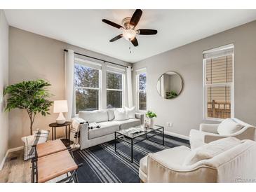 Bright living room features a ceiling fan, large windows, modern furniture, and a striped area rug at 2820 Macon Way, Denver, CO 80238