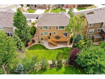 An aerial view of a well-manicured backyard with a lawn, mature trees, and a wooden deck at 1997 Fox Haven Dr, Castle Rock, CO 80104
