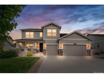 Charming two-story home with a well-maintained lawn, covered porch, and a two-car garage at dusk at 12032 Triple Crown Dr, Parker, CO 80134