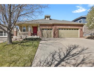 Charming brick home featuring a three-car garage, front porch, and well-maintained lawn at 2775 S Jebel Way, Aurora, CO 80013