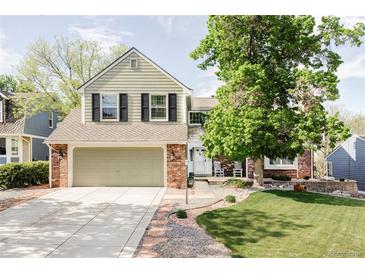 Charming two-story home with a well-manicured lawn, brick accents, and an attached two-car garage at 9867 W Berry Dr, Littleton, CO 80123