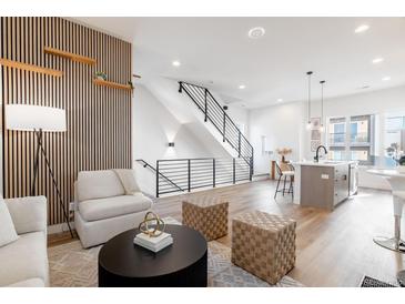 Open-concept living room featuring modern decor, hardwood floors, and a stylish staircase at 2900 W Parkside Pl, Denver, CO 80221