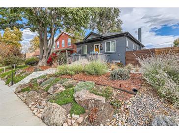 Landscaped front yard with rocks and plants leading to a charming blue house at 1538 Albion St, Denver, CO 80220