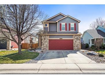 Charming two-story home with gray siding, brick accents, red garage door, and red shutters on a sunny day at 6190 Sparrow Ave, Firestone, CO 80504