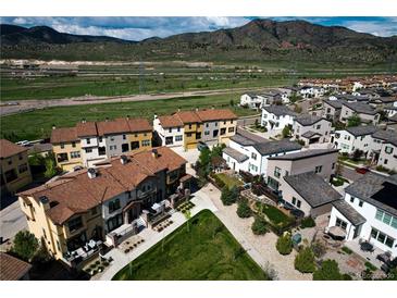 Stunning aerial view of a neighborhood with mountain backdrop showcasing well-maintained homes and green spaces at 15576 W Washburn Cir, Lakewood, CO 80228