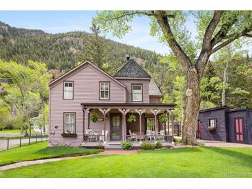 Charming two-story home with a covered porch and a well-manicured lawn against a mountain backdrop at 715 Main St, Georgetown, CO 80444