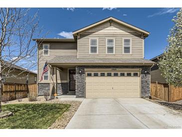 Charming two-story home featuring stone accents, a two-car garage, and a well-manicured front yard with an American flag at 25621 E Cedar Pl, Aurora, CO 80018
