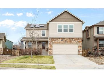 Two-story home with stone accents, a well-manicured lawn, and a two-car garage for convenient parking at 12715 E 104Th Pl, Commerce City, CO 80022