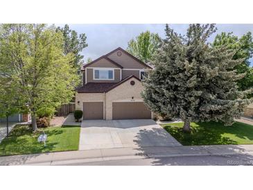 Charming two-story home with a brick facade, mature trees, and a well-manicured lawn at 16158 Whitestone Dr, Parker, CO 80134