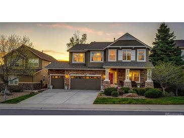 Charming two-story home with a stone facade, inviting front porch, and lush landscaping at sunset at 4307 Lilly Gulch Trl, Castle Rock, CO 80109