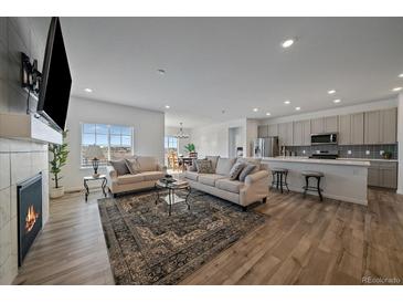 Open-concept living room features hardwood floors, plush couches, and an adjacent kitchen with modern appliances at 18001 Herrera Dr, Parker, CO 80134