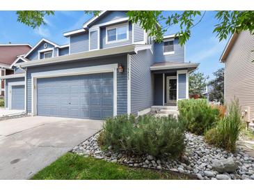 Two-story home with blue siding, a gray garage door, and river rock landscaping in front at 5453 S Quatar Ct, Aurora, CO 80015
