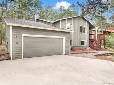 Charming gray two-story home with a two-car garage and a red staircase leading to the front deck at 510 Silhouette Way, Monument, CO 80132
