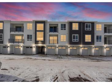 Modern two-story townhome building with attached garages and snow-covered parking lot at 6153 N Ceylon St # 201, Denver, CO 80249