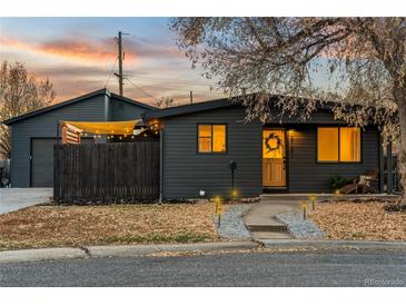 Charming home featuring a dark exterior, inviting front yard, and cozy outdoor lighting, perfect for evening enjoyment at 8120 W 54Th Pl, Arvada, CO 80002