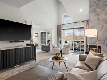 Open-concept living room featuring high ceilings, a modern fireplace, and a large window overlooking the neighborhood at 345 Fillmore St # 407, Denver, CO 80206