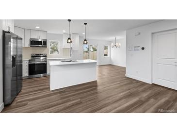 A modern kitchen featuring an island, stainless steel appliances, and hardwood floors at 5292 Columbine Ln, Denver, CO 80221