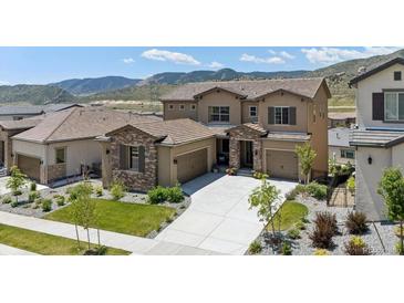 Two-story stucco home with tile roof, attached garage, concrete driveway and mountain views at 2125 S Orion St, Lakewood, CO 80228