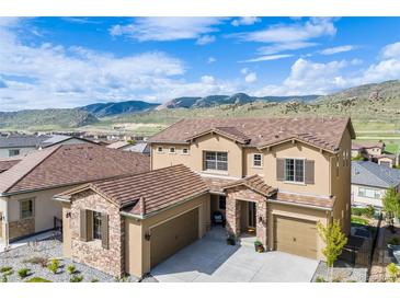 Beautiful two-story home with a three car garage and a stone archway entrance; mountain views can be seen in the background at 2125 S Orion St, Lakewood, CO 80228