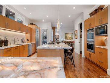 Modern kitchen features wooden cabinets, marble countertops, stainless steel appliances, and an island with bar seating at 402 Garfield St, Denver, CO 80206