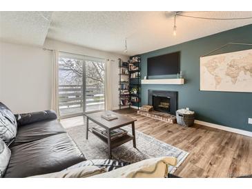 Cozy living room with fireplace, TV, and sliding door to balcony at 3141 S Tamarac Dr # 202E, Denver, CO 80231