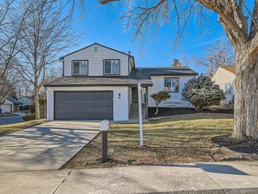 Two-story home featuring a gray garage door, well-maintained lawn, and manicured landscaping at 4591 S Fairplay St, Aurora, CO 80015