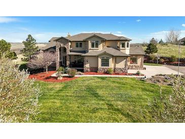 Stunning two-story stucco home with stone accents, mature landscaping, and a well-manicured front lawn at 3891 Windchant Cir, Castle Rock, CO 80104