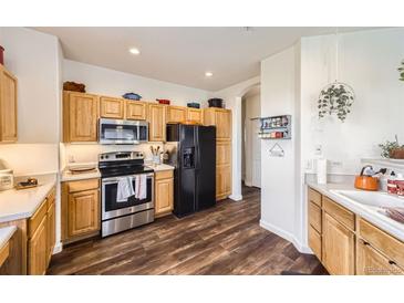 Bright kitchen features stainless steel appliances, wooden cabinets, and wood-look flooring at 8976 Fox Dr # 101, Thornton, CO 80260