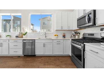 Bright kitchen features white cabinets, stainless steel appliances, hardwood floors, and natural light at 7856 W 43Rd Pl, Wheat Ridge, CO 80033