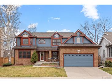 Charming two-story home featuring brick and blue siding, complemented by a well-maintained front yard and two-car garage at 16234 E Belleview Dr, Centennial, CO 80015