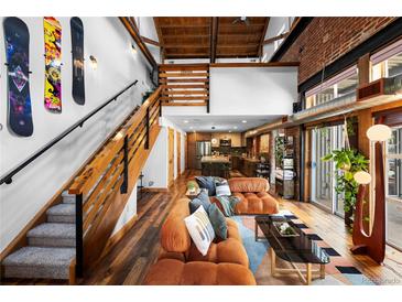 Spacious living room featuring exposed wood beams, an open staircase, and comfortable seating at 3033 Blake St # 109, Denver, CO 80205