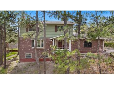 Charming two-story home with brick and siding exterior, surrounded by trees at 1185 Fawnwood Rd, Monument, CO 80132