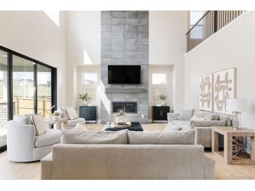 Grand living room featuring a soaring ceiling, fireplace with tile accents, and comfortable seating at 14247 Beebalm Loop, Parker, CO 80134