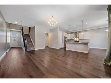 Bright living room featuring hardwood floors, staircase, and open access to a modern kitchen at 12255 Hazel Spruce Ct, Parker, CO 80134