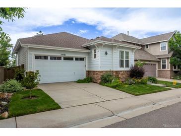 Charming home with an attached garage, stone accents, a well-manicured lawn, and beautiful landscaping at 10581 Pearlwood Cir, Highlands Ranch, CO 80126