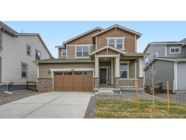 Inviting two-story home with a charming front porch, a well-manicured lawn, and an attached two-car garage at 5601 Inland Ave, Firestone, CO 80504