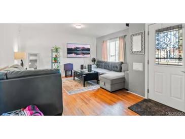 Inviting living room featuring hardwood floors, gray sofa, and a modern entertainment center at 1315 Xanthia St, Denver, CO 80220