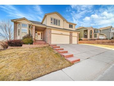 Charming two-story house with brick accents, three-car garage, and well-manicured lawn at 15972 W 70Th Dr, Arvada, CO 80007