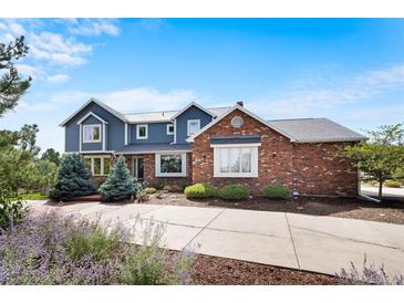 Charming two-story home with a combination of blue siding and brick, complemented by a well-manicured lawn and a long driveway at 19052 E Briarwood Dr, Centennial, CO 80016