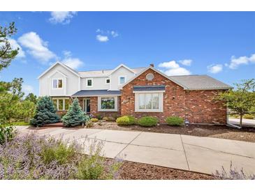 Charming brick and siding home with manicured landscaping and mature trees under a sunny sky at 19052 E Briarwood Dr, Centennial, CO 80016