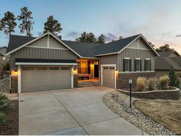 Inviting exterior view showcasing a two-car garage, stylish stonework, and well-manicured landscaping at 1775 Catnap Ln, Monument, CO 80132