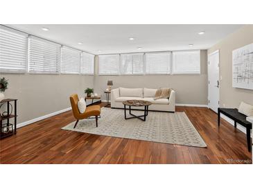 Cozy living room featuring wood floors, neutral walls, and natural light from large windows with white blinds at 909 N Logan St # 1B, Denver, CO 80203