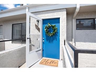 Charming condo front entrance features a vibrant blue door adorned with a welcoming wreath and 'Hello' doormat at 1830 Newland Ct # 321, Lakewood, CO 80214