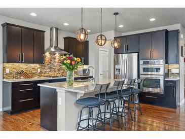 Modern kitchen featuring dark cabinets, stainless steel appliances, granite countertops, and an island with seating at 15275 W La Salle Ave, Lakewood, CO 80228