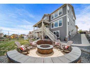 Spacious backyard featuring a fire pit area with seating, a two-story home and a lush lawn at 23879 E Narrowleaf Pl, Aurora, CO 80016