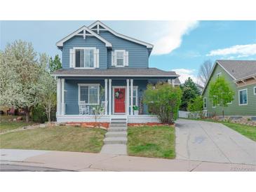 Charming blue two-story home with a welcoming red door, white porch columns, and a well-manicured lawn at 3186 Springmeadow Cir, Castle Rock, CO 80109
