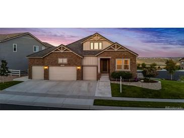 Inviting brick and siding home featuring a three-car garage, manicured lawn, and a cozy, well-lit entrance at 15994 La Plata Peak Pl, Broomfield, CO 80023