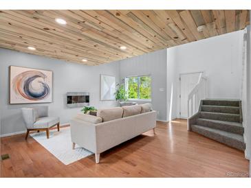 Bright living room featuring a wood ceiling, hardwood floors, and modern fireplace at 13245 Shoshone St, Denver, CO 80234