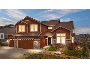 Charming two-story home with red siding, stone accents, manicured landscaping, and a spacious two-car garage at 3234 El Charro Pt, Castle Rock, CO 80108